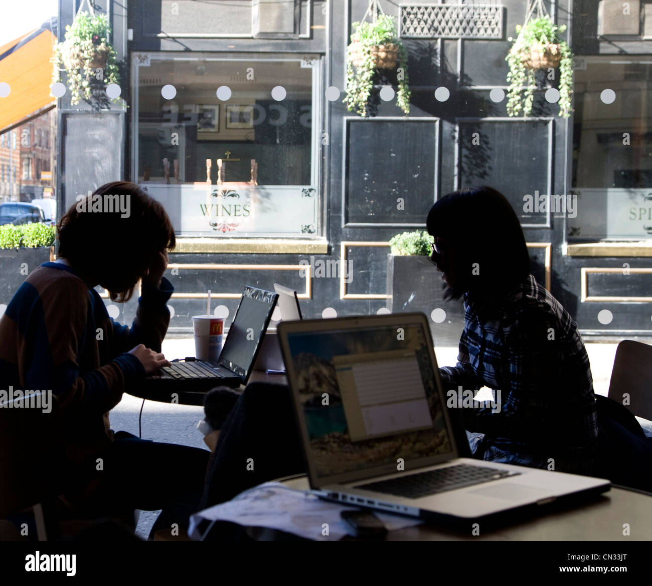 Zwei Mädchen in der Silhouette in einem Café, Blick auf Runde top Computer Stockfoto