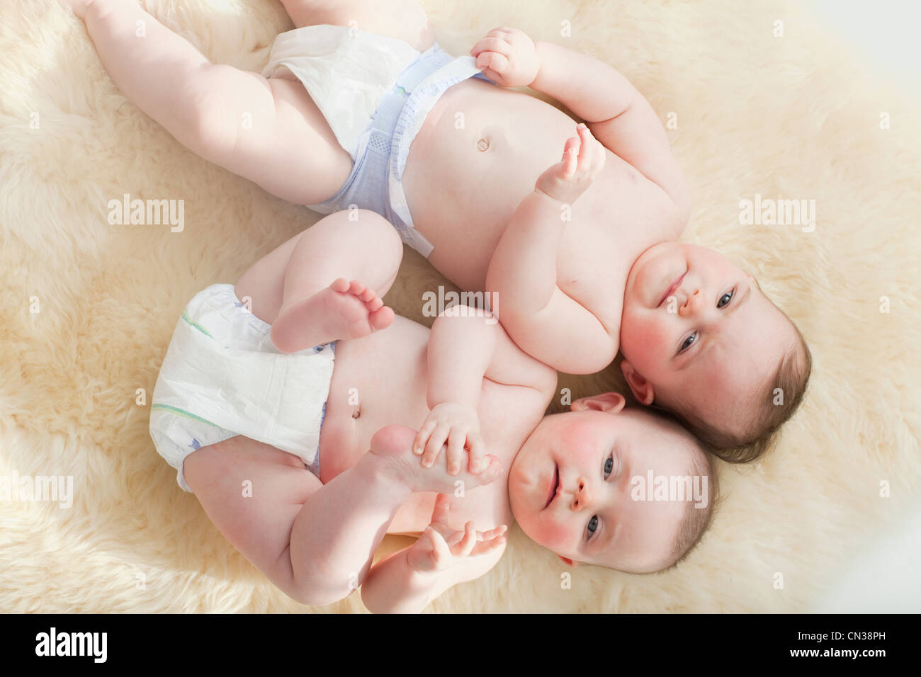 Zwillinge Baby liegend auf einem Schaffell-Teppich Stockfoto