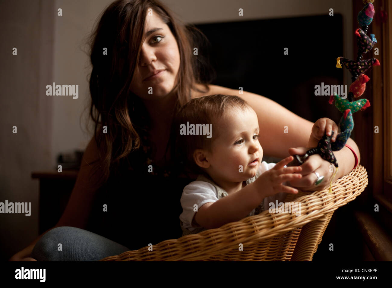 Glückliches lächelndes Baby spielt in schönes Licht mit Katze und Mutter Stockfoto