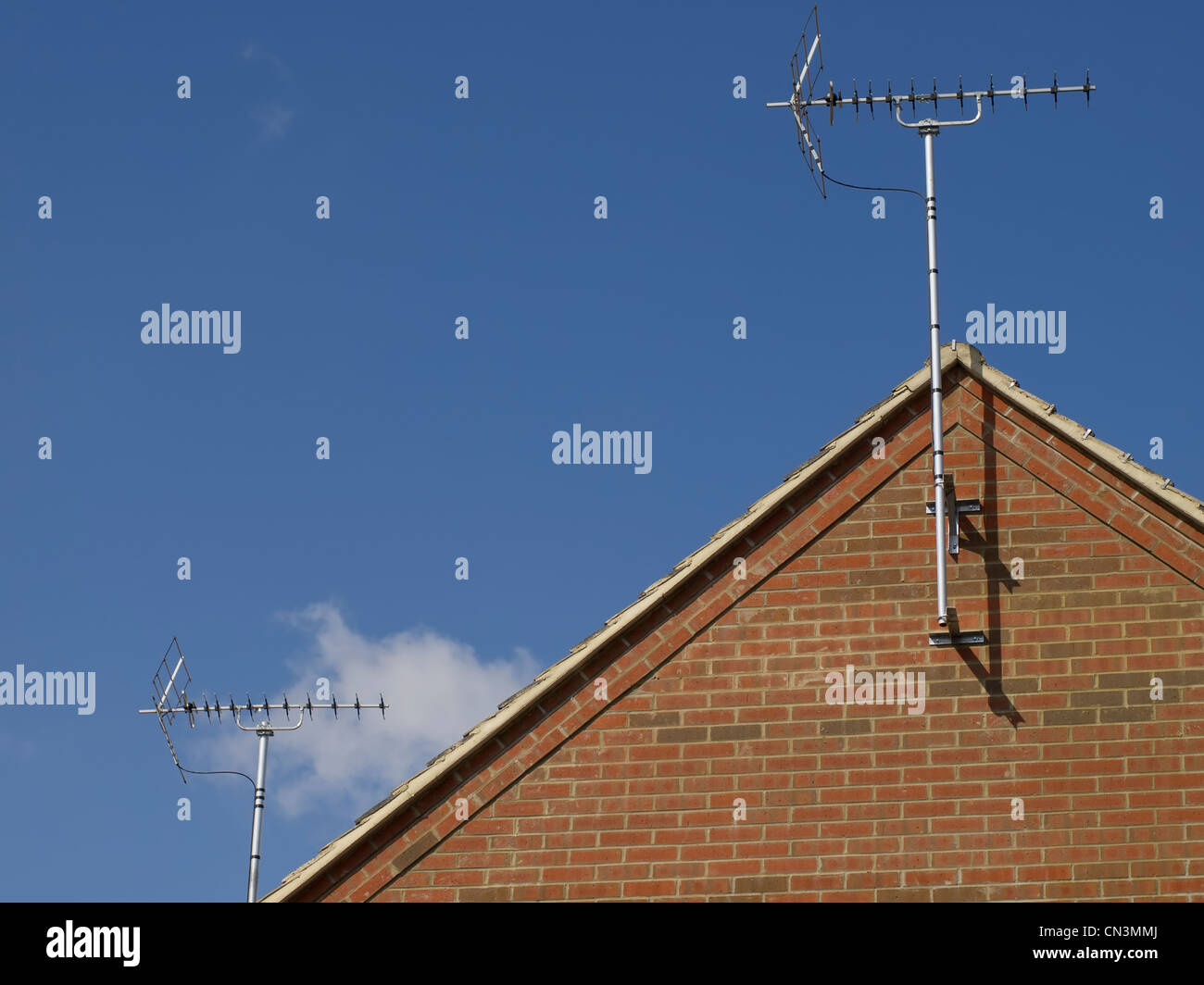 TV Antenne auf einem Hausdach, umrahmt von einem blauen Himmel. Stockfoto