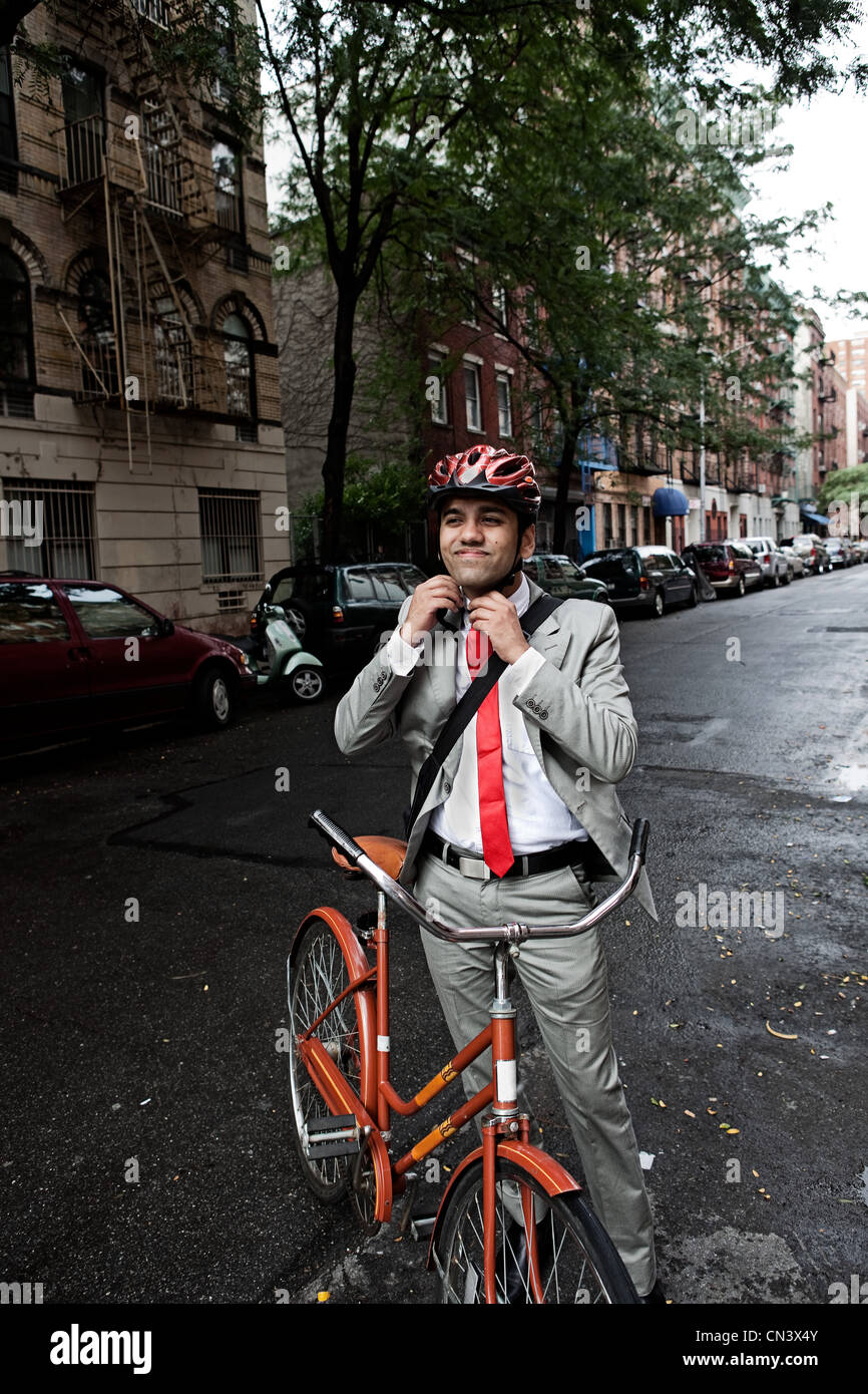 Junger Geschäftsmann Fahrradhelm in der Straße anpassen Stockfoto