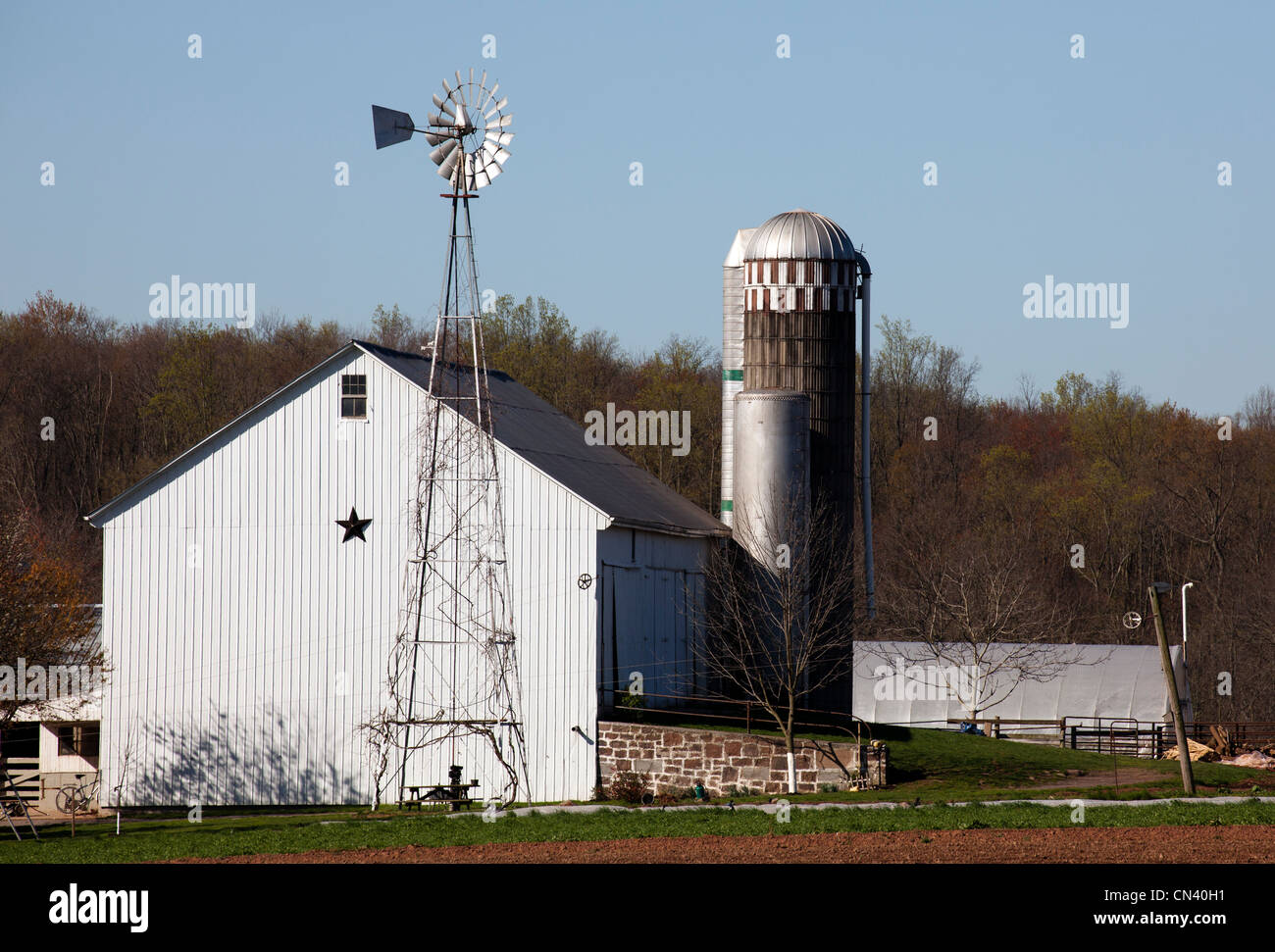 Wasserpumpen Windmühle vor einer amischen weiße Scheune. Stockfoto