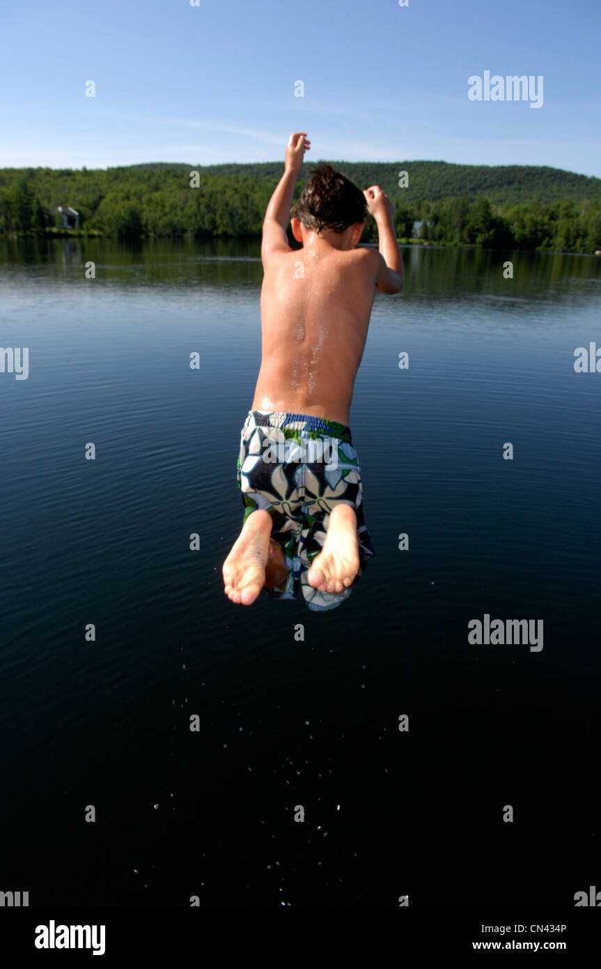 Young Boy springen weg von einem Dock, Lac des Neiges, Quebec Stockfoto