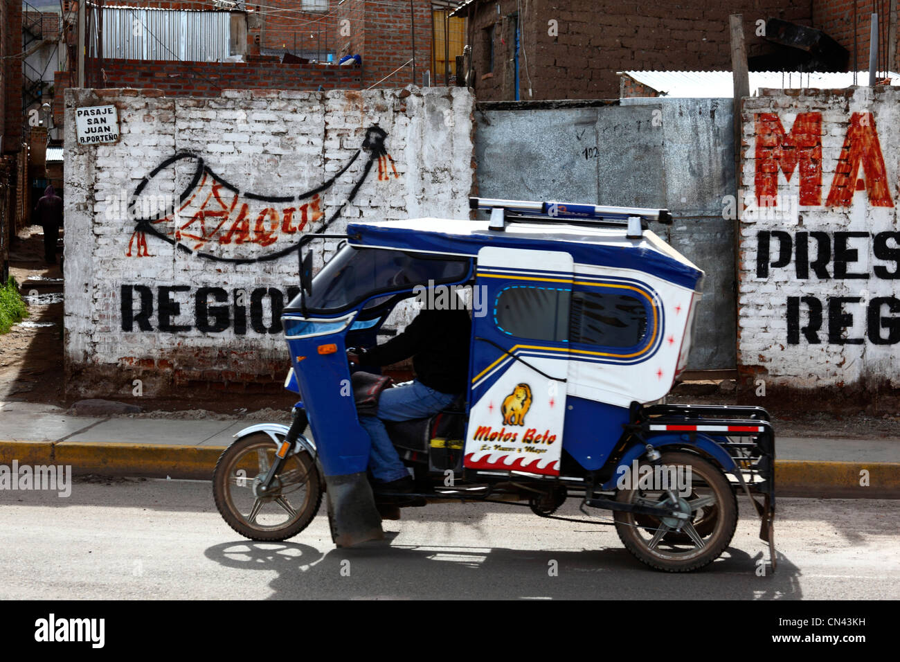 Motorisiertes Dreiradtaxi (Mototaxi), vorbei an Parteiplaketten und Propaganda, die an der Wand gemalt wurden, Puno, Peru Stockfoto