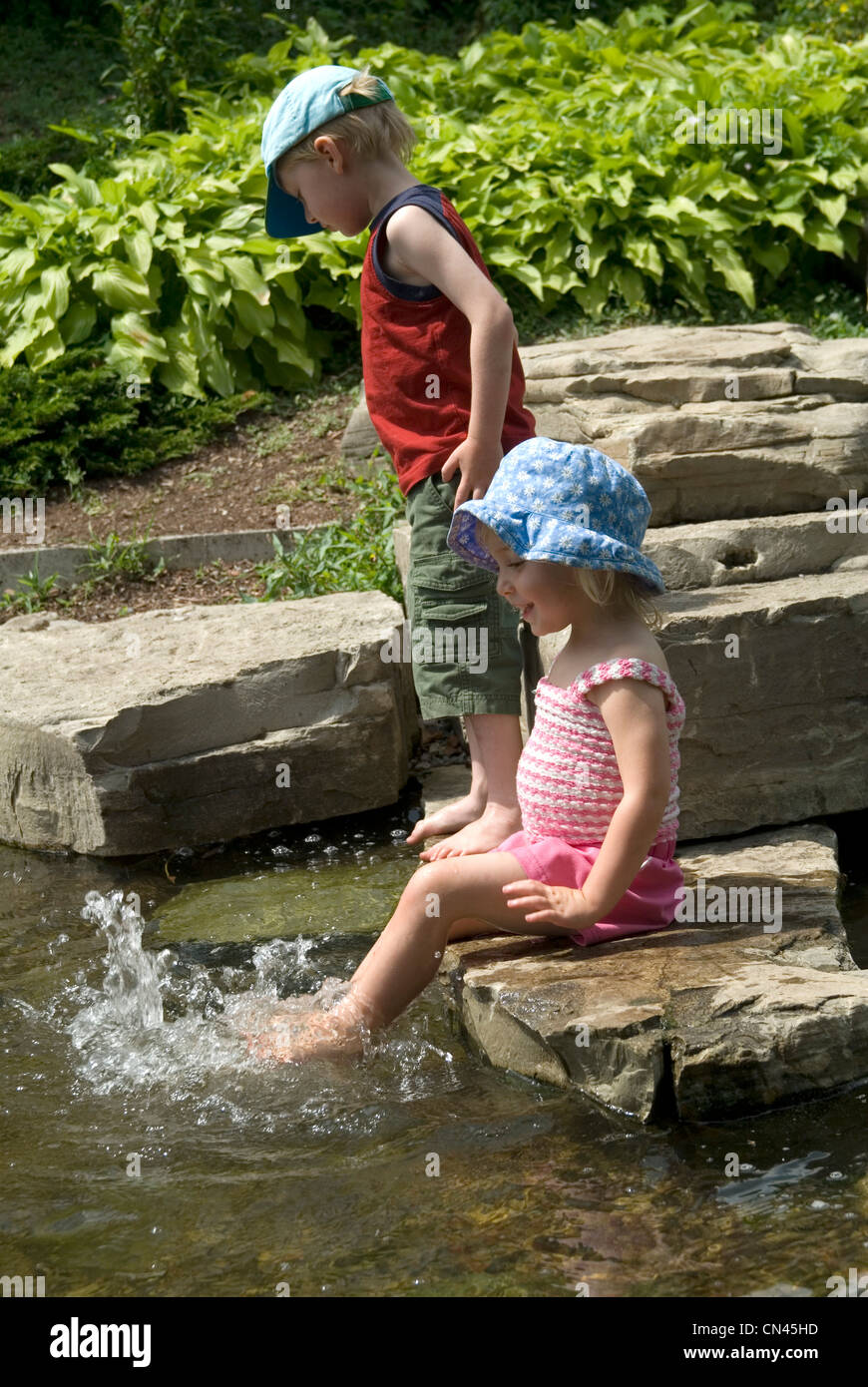 Bruder und Schwester spielen in einem Teich, Scotts Plains Park, entlang des Otonabee River, Peterborough, Ontario Stockfoto