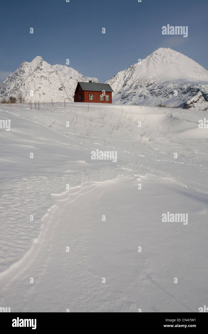 Norwegen, Troms Grafschaft, Lyngen Alpen, rote Holzhütte mit Bergen im Hintergrund in der Nähe von Svensby Stockfoto