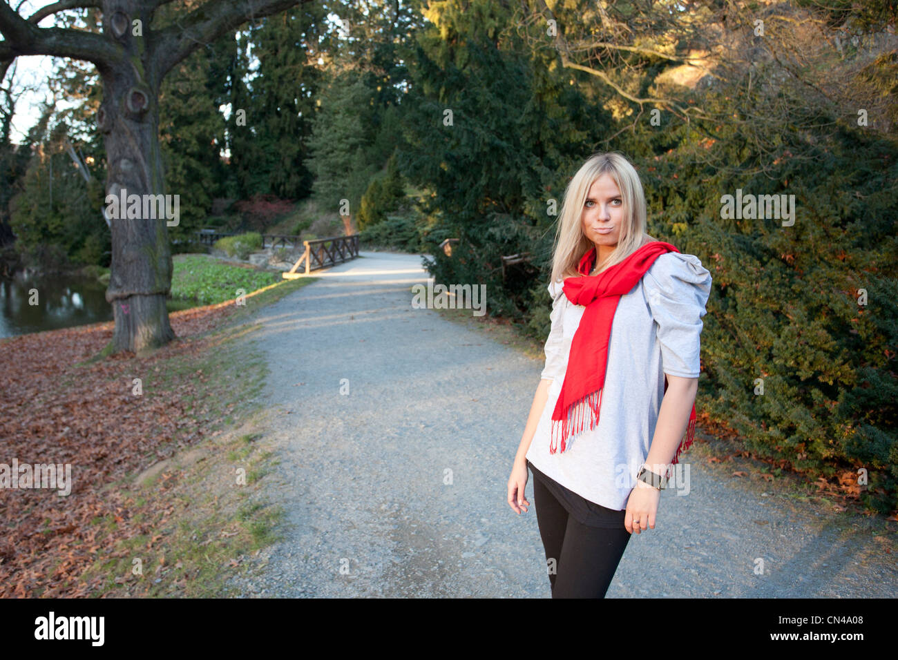 Frau mit rotem Schal, die auf einem Park Pathway in der Dämmerung läuft. Stockfoto