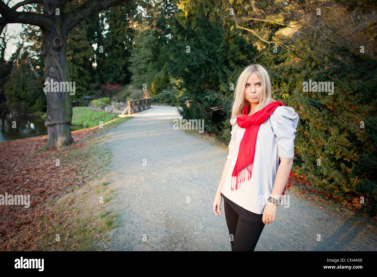 Frau mit rotem Schal, die auf einem Park Pathway in der Dämmerung läuft. Stockfoto