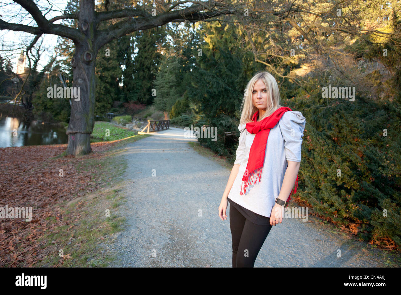 Frau mit rotem Schal, die auf einem Park Pathway in der Dämmerung läuft. Stockfoto