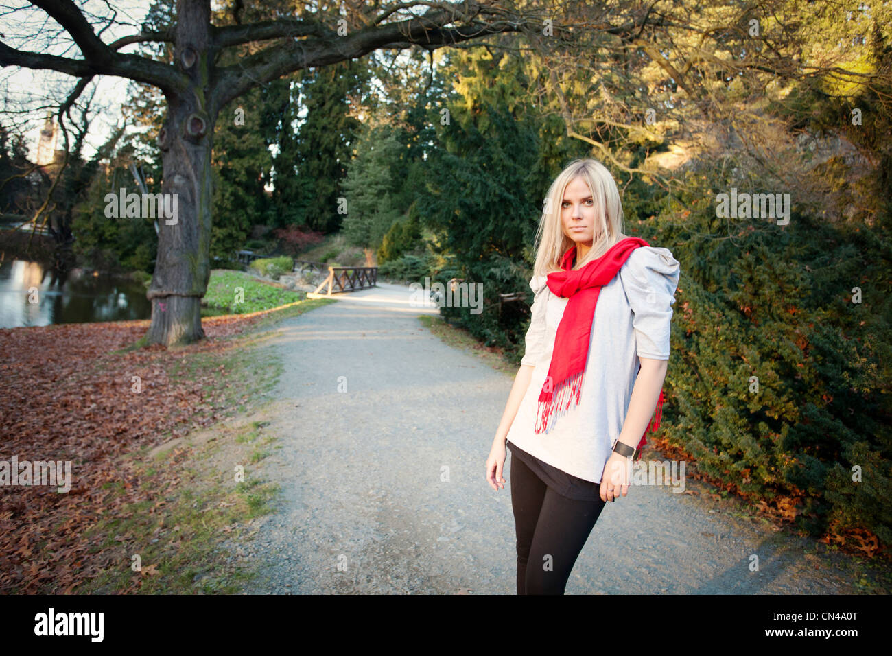 Frau mit rotem Schal, die auf einem Park Pathway in der Dämmerung läuft. Stockfoto