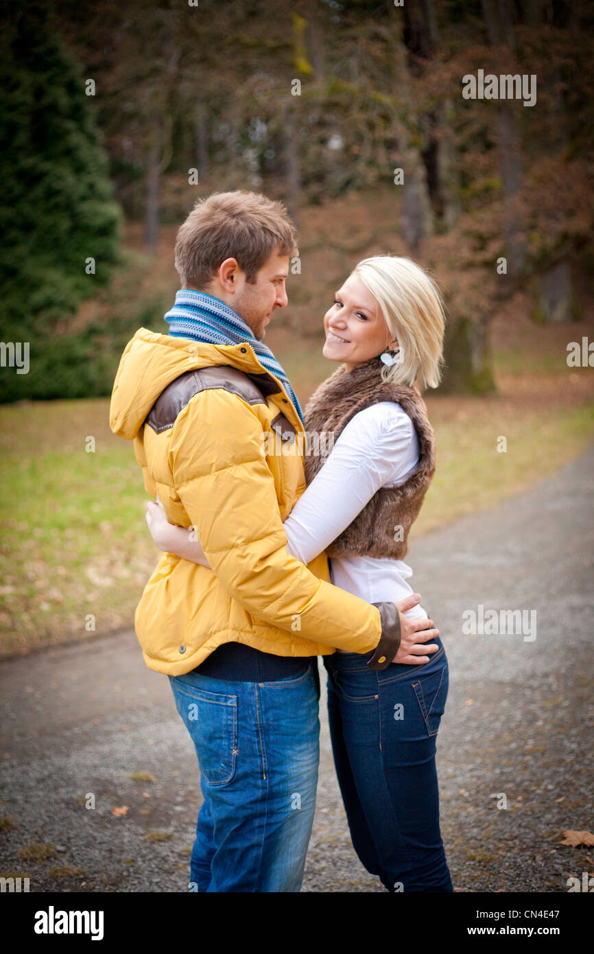 Junges Paar umarmt im Freien. Ein junger Mann und eine junge Frau halten sich während eines Spaziergangs in einem Park an einem kalten Winternachmittag in der Hand. Stockfoto