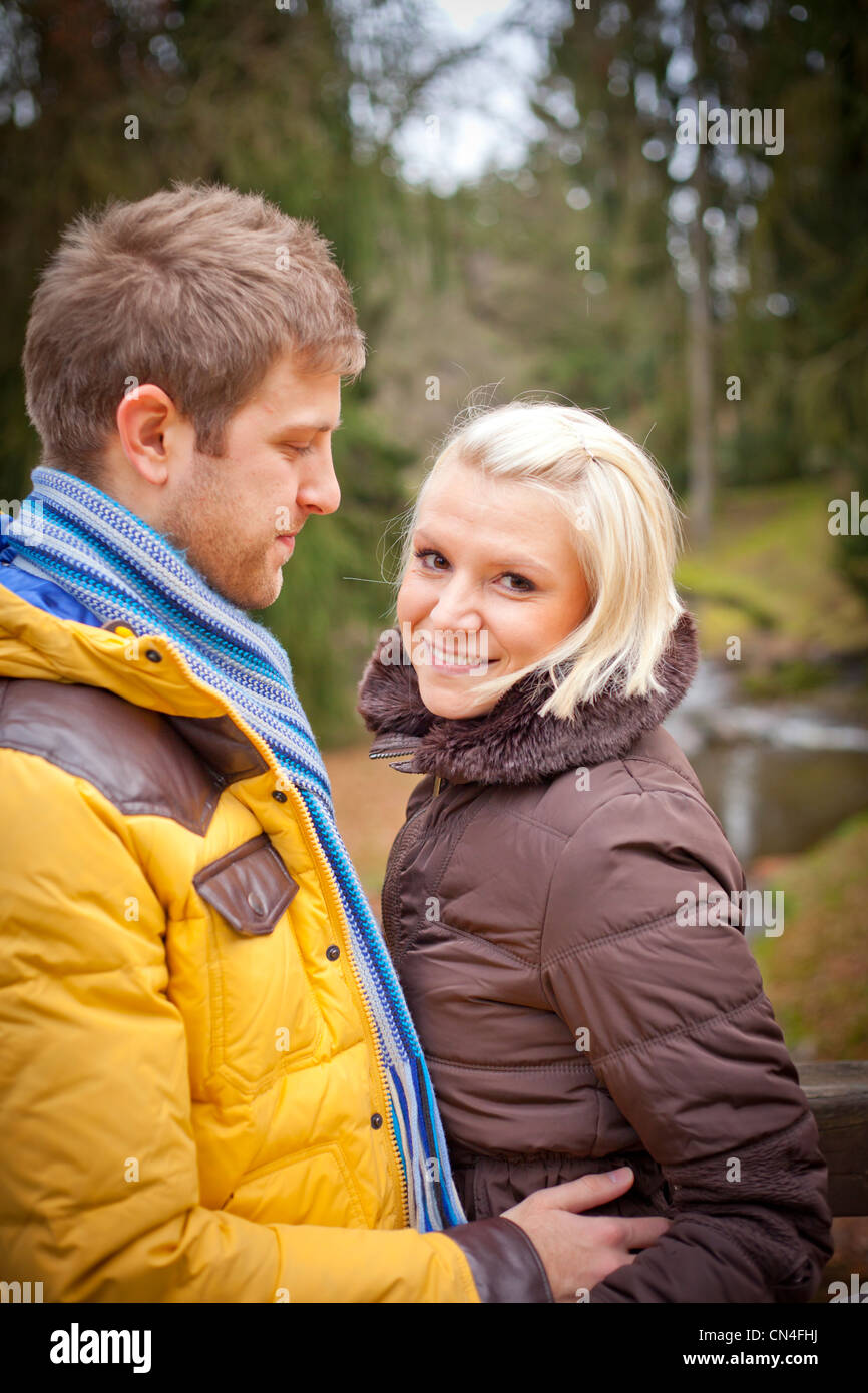 Junges Paar umarmt im Freien. Ein junger Mann und eine junge Frau halten sich während eines Spaziergangs in einem Park an einem kalten Winternachmittag in der Hand. Stockfoto