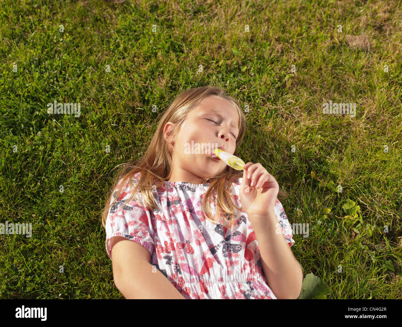 Mädchen genießen Eis am Stiel auf Rasen Stockfoto