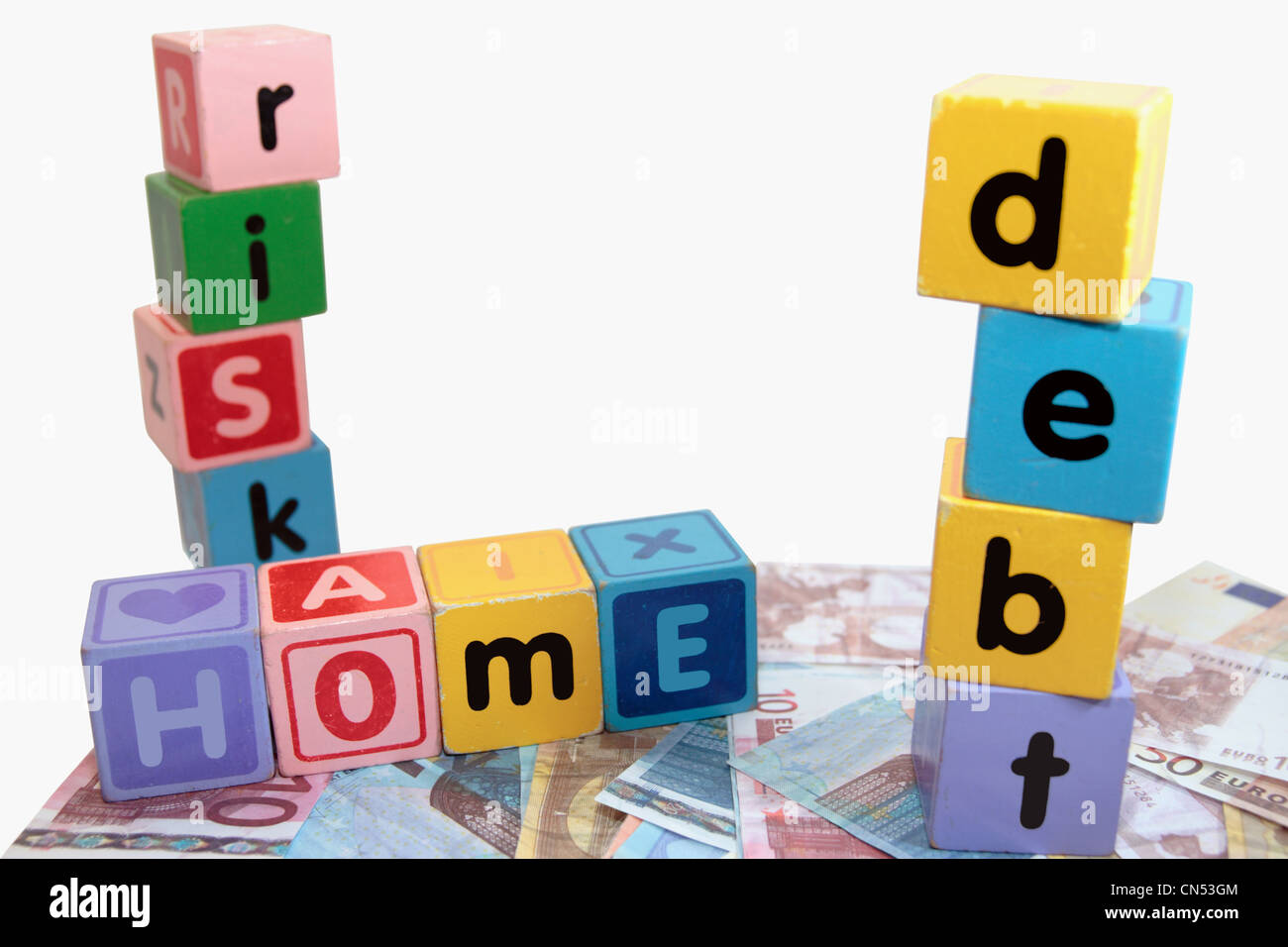 verschiedene Kinder Spielzeug Bausteine Brief vor einem weißen Hintergrund auf Geld, die Heimat Schulden Risiko buchstabieren Stockfoto