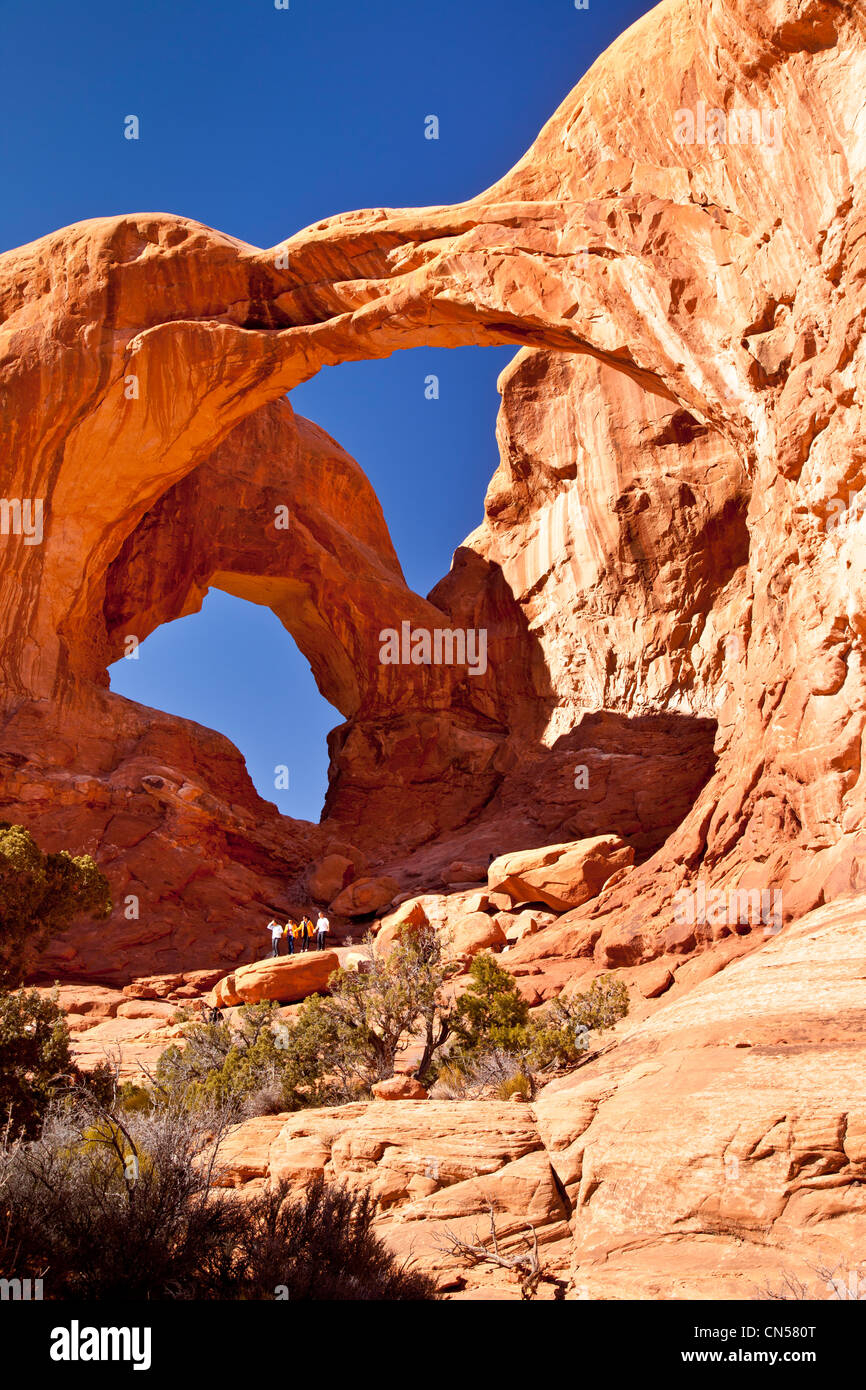 Touristen-Pose unter Double Arch im Arches-Nationalpark, Utah, USA Stockfoto