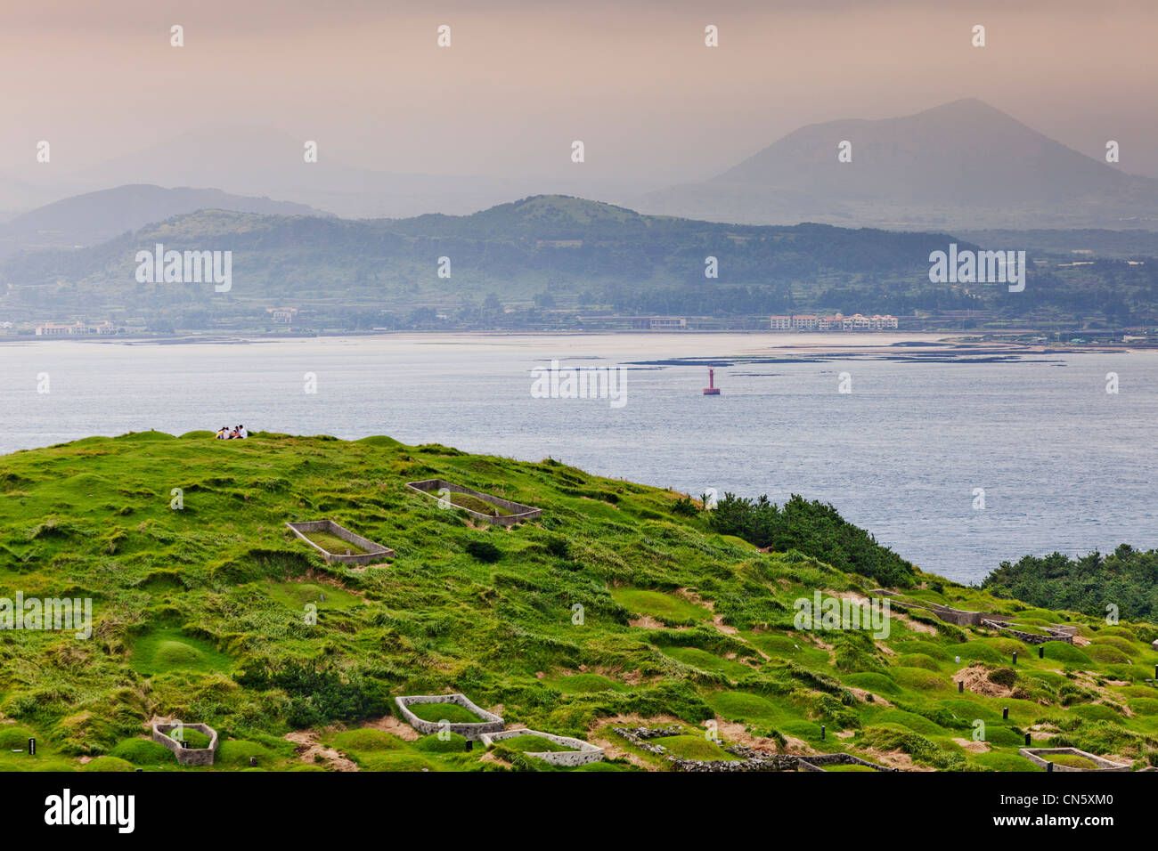 Südkorea, Provinz Jeju, U Island, Gräber und Jeju Island im Hintergrund Stockfoto