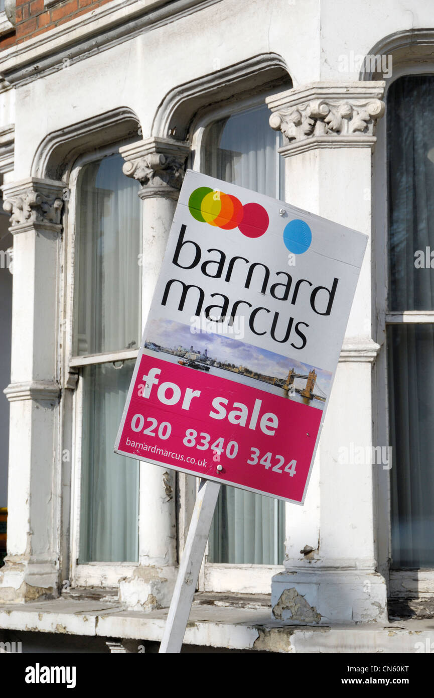 Immobilienmakler "zu verkaufen" an Bord vor einem verfallenen Haus renovierungsbedürftig Stockfoto