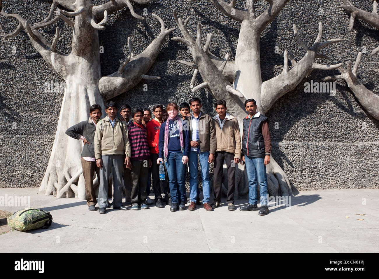 Punjabi College-Studenten stellen mit einem westlichen Touristen vor konkreten Bäumen in Steingärten von Chandigarh in Punjab Stockfoto