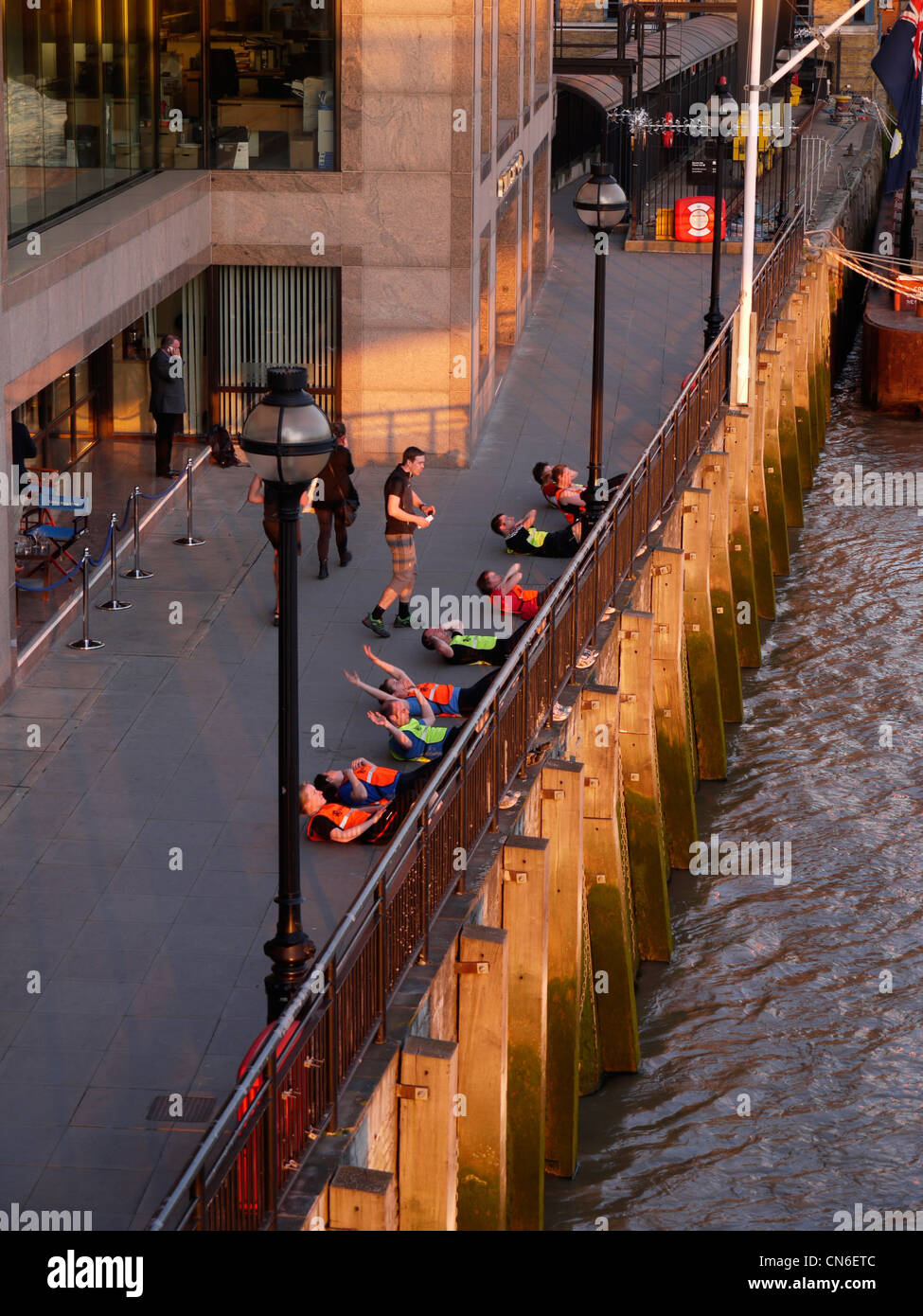 Personal Trainer leitet eine Bootcamp-Gruppe, die Sit-UPS an der Themse im Zentrum von London macht Stockfoto