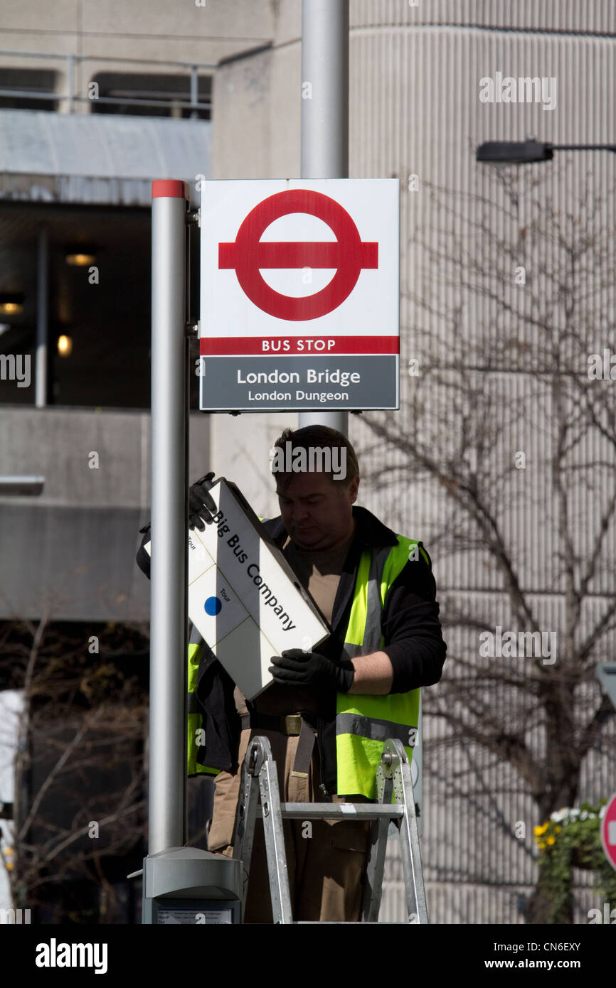 Arbeiter reparieren Informationen zur Bushaltestelle für big Bus Company, London Bridge, London Stockfoto
