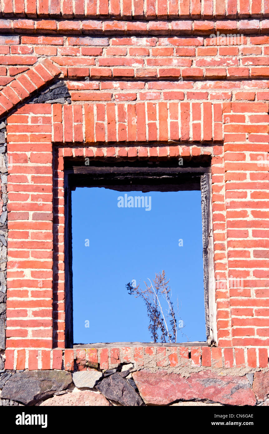 Hintergrund der verbrannten alten verlassenen Gebäude aus rotem Backstein Mauer und blauer Himmel im Fensterbogen. Stockfoto