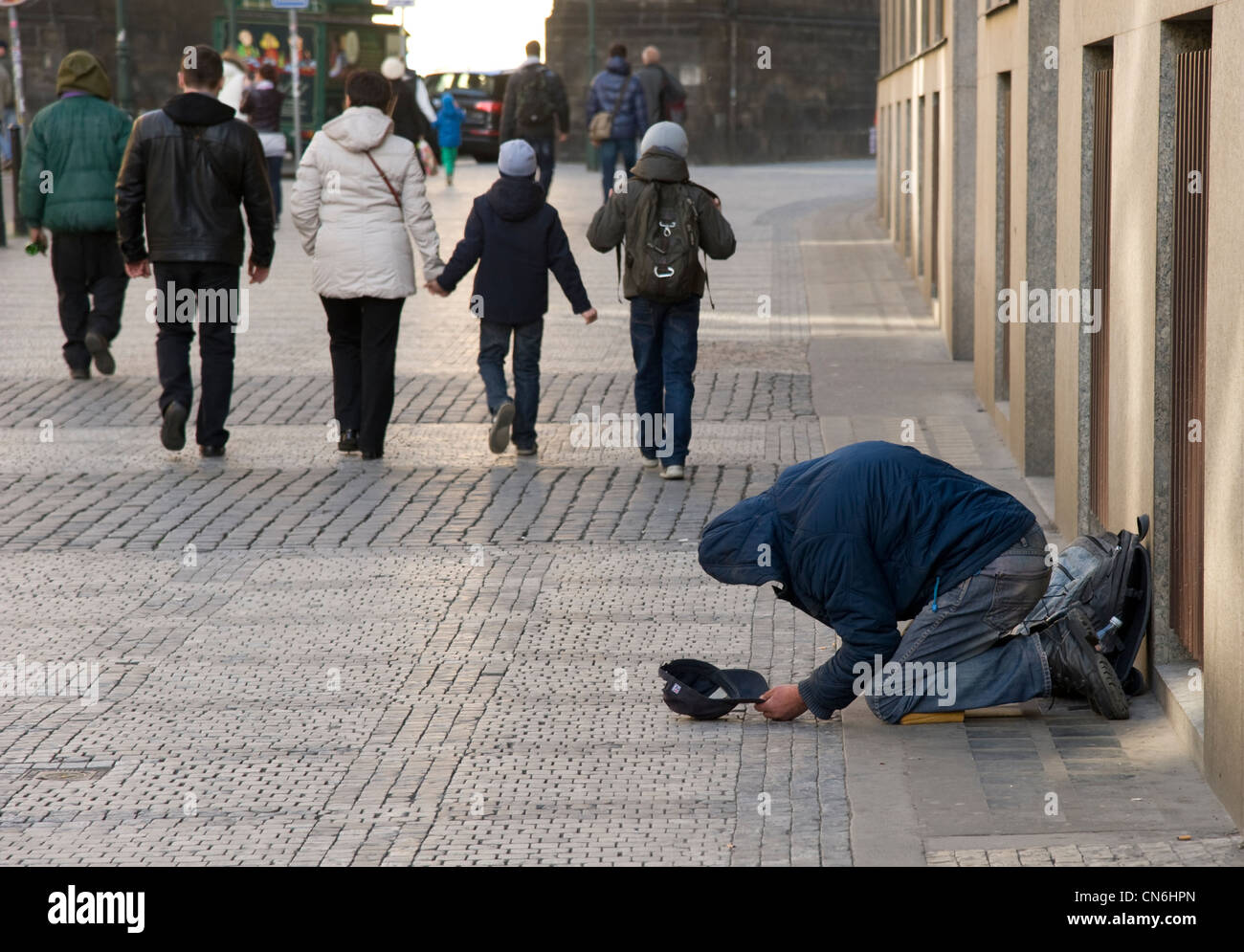 Prag. Tschechische Republik. April 2012. Ein Obdachloser bettelt auf der Straße, wie Leute vorbeigehen gleichgültig von seiner Lage. Stockfoto