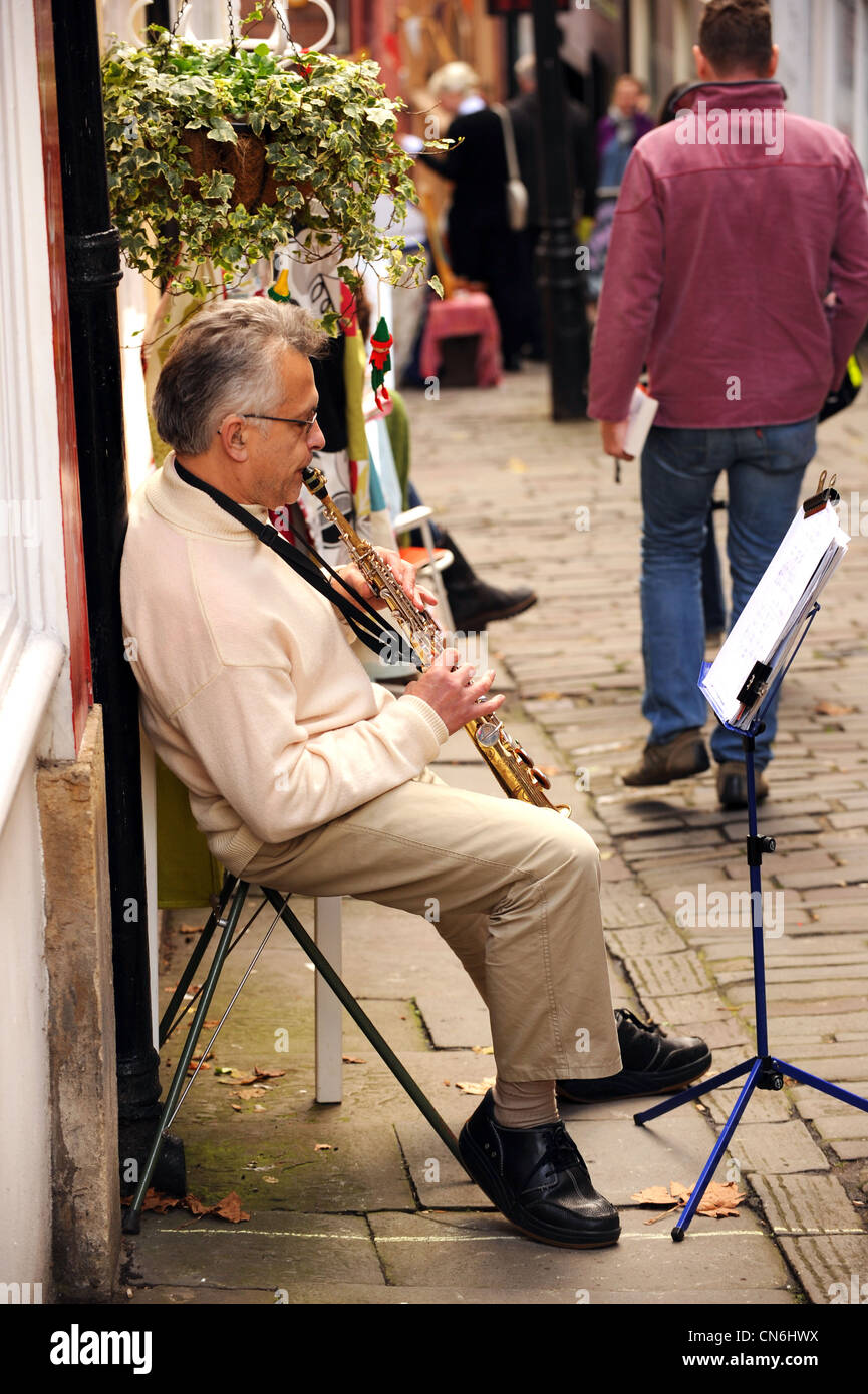 Bristol. England. November 2010. Ein Straßenmusikant spielt in einer schmalen Gasse. Stockfoto