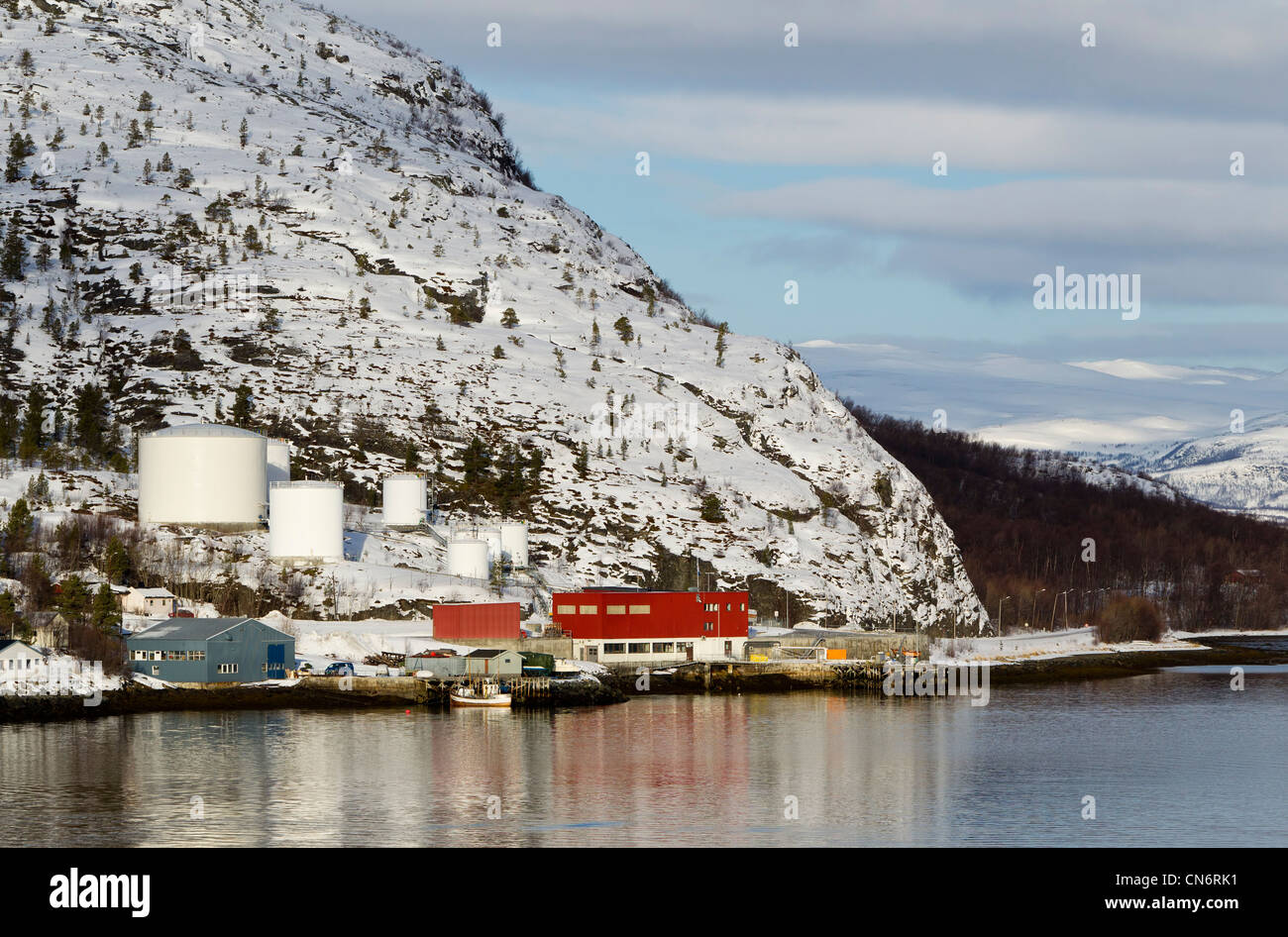 Ein Öl-Lager am Ufer an einem Fjord mit Schnee bedeckt Berg hinten genommen im Querformat Stockfoto