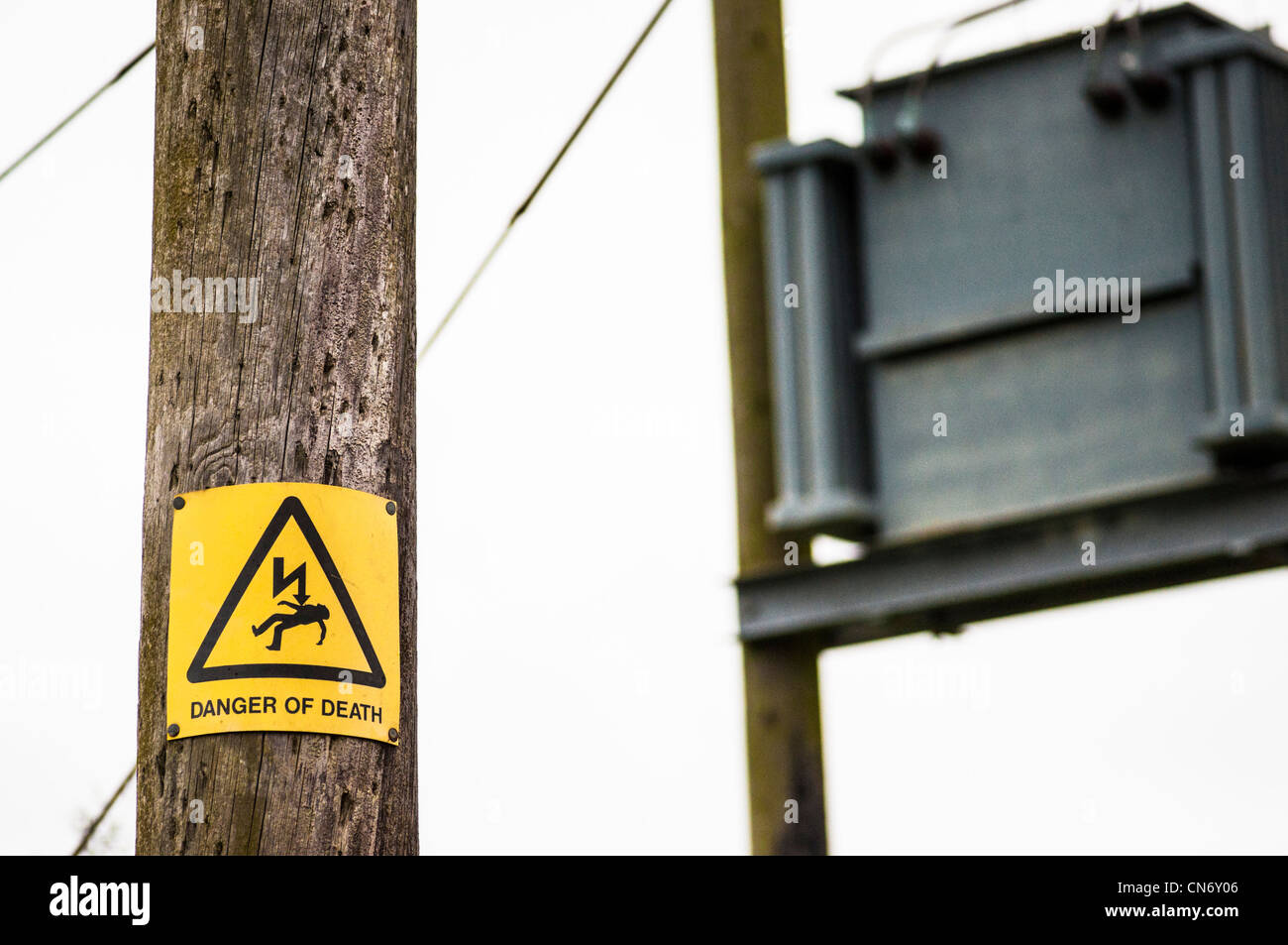 Gefahr des Todes gelb Warnzeichen auf einen Telegrafenmast mit Strom Anschlusskasten & Kabel. Stockfoto