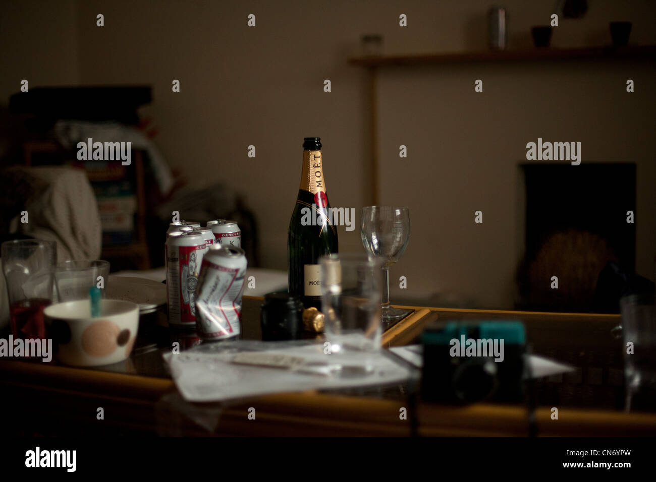 Eine leere Flasche Champagner und Bierdosen in einem Zimmer nach einer Party in einem Studentenhaus. Stockfoto