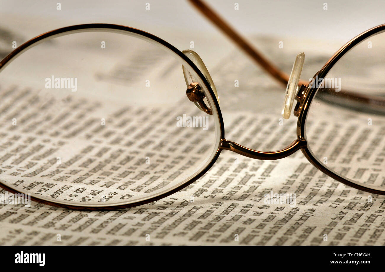 Brillen und eine Zeitung ruhen auf dem Tisch. Stockfoto