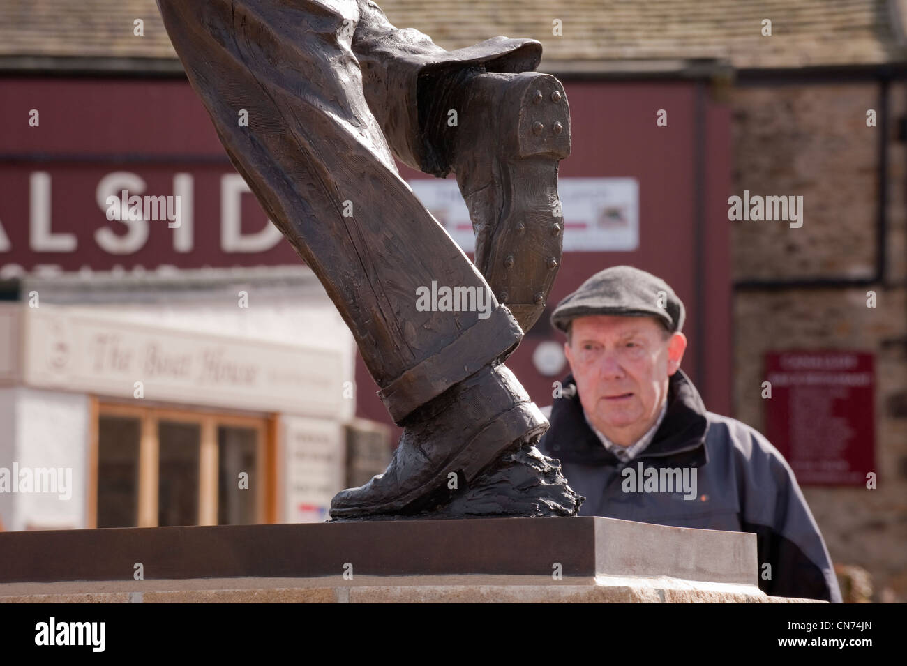 1 mann an der Bronzestatue von cricketer Fred (Freddie) Trueman (Füße & Beine von schnellen Bower in Aktion) - Skipton, North Yorkshire, England, UK. Stockfoto