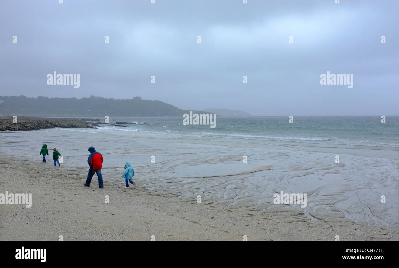 Eine Familie auf Gyllyngvase Strand in Cornwall auf einem nassen und windigen Tag Stockfoto