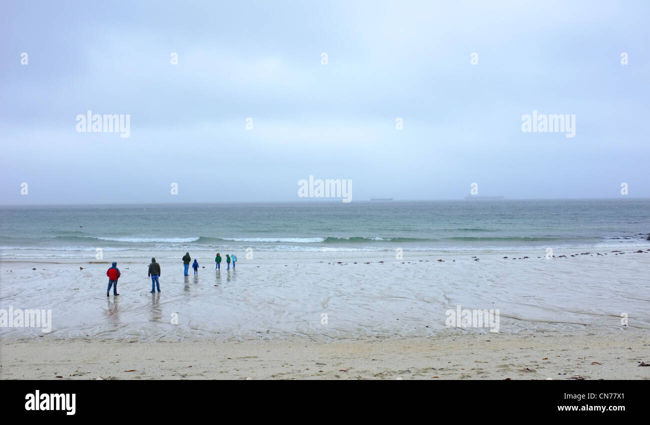 Eine Familie auf Gyllyngvase Strand in Cornwall auf einem nassen und windigen Tag Stockfoto