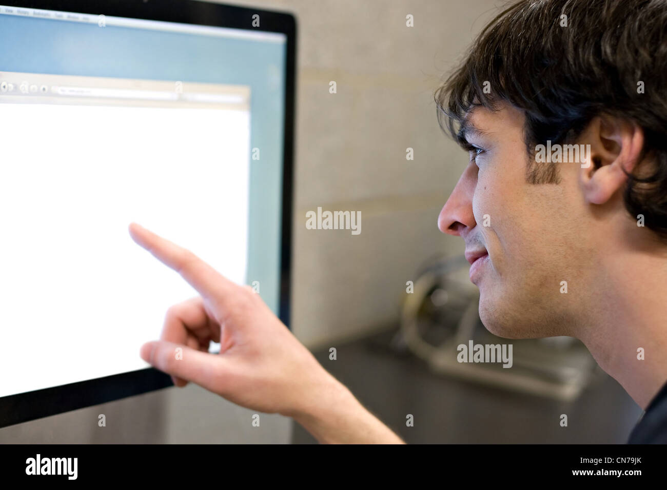 Ein junger Mann auf einem modernen Computer monitor lcd mit Exemplar. Geringe Schärfentiefe mit stärksten Fokus auf das Gesicht. Stockfoto