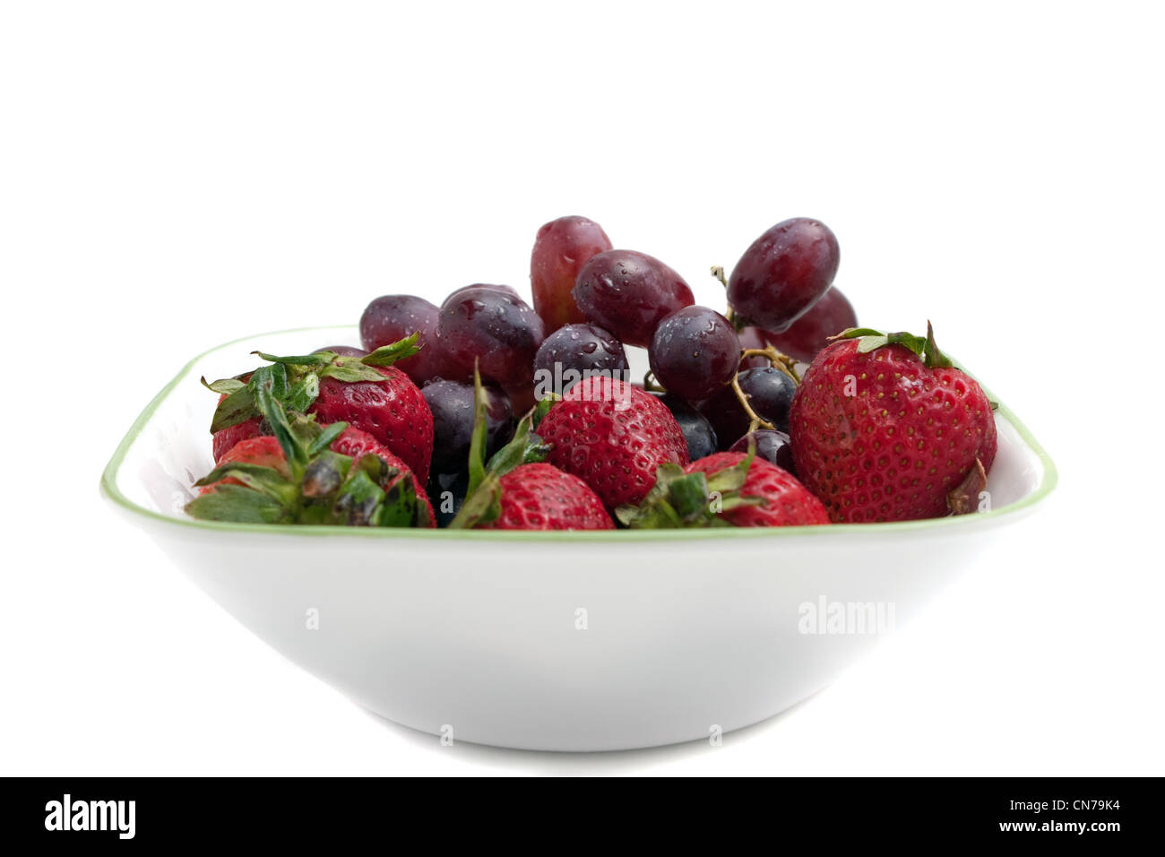 Eine Schale mit roten Antioxidans reiche Beeren darunter rote kernlose Trauben und frischen Reifen Erdbeeren. Stockfoto