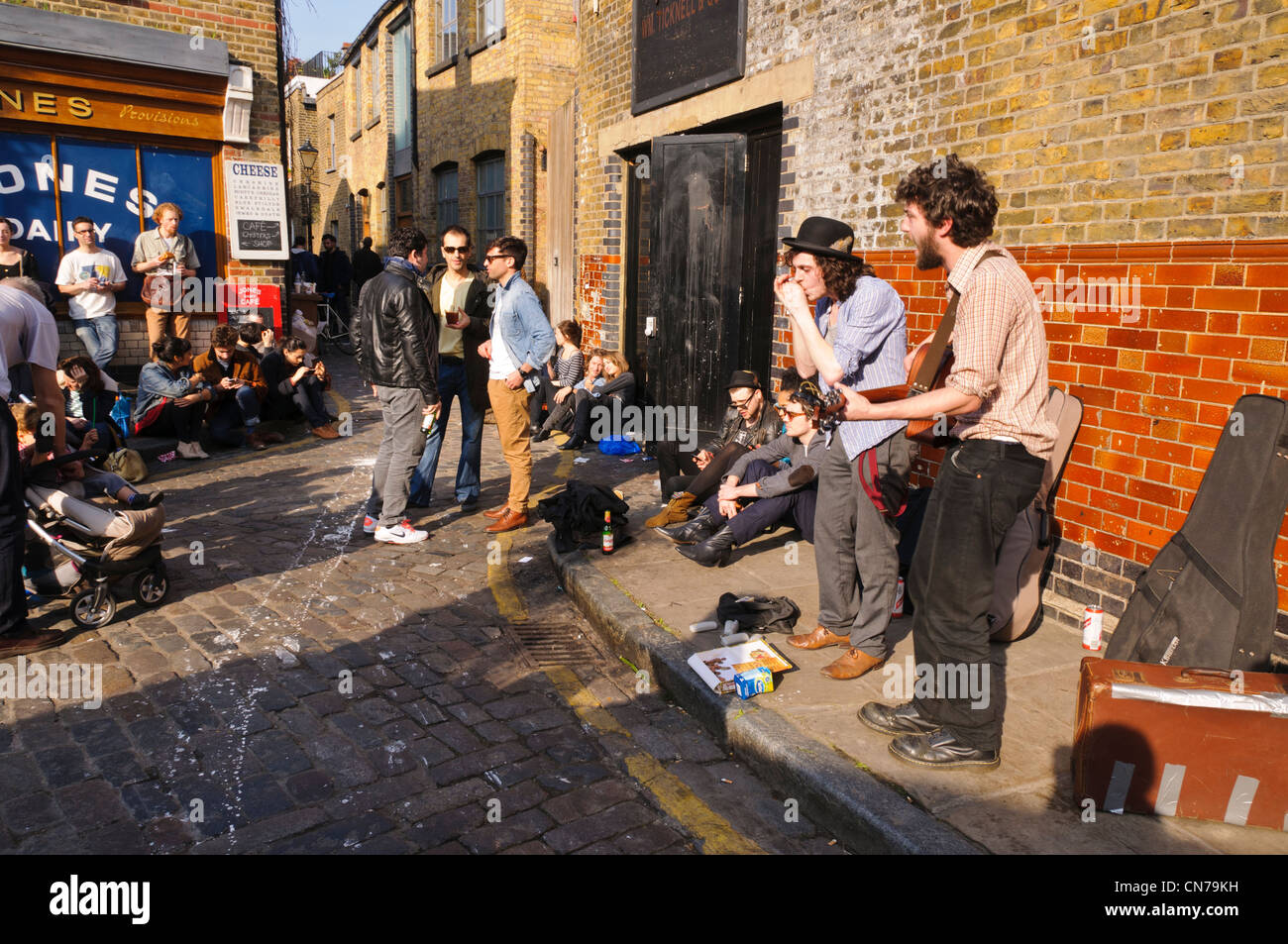 Zwei junge Buskers Gitarre spielen und singen auf der Straße, East London Stockfoto