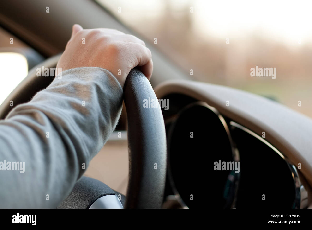Eine Frau hält das Lenkrad eines Autos mit einer Hand während der Fahrt. Stockfoto