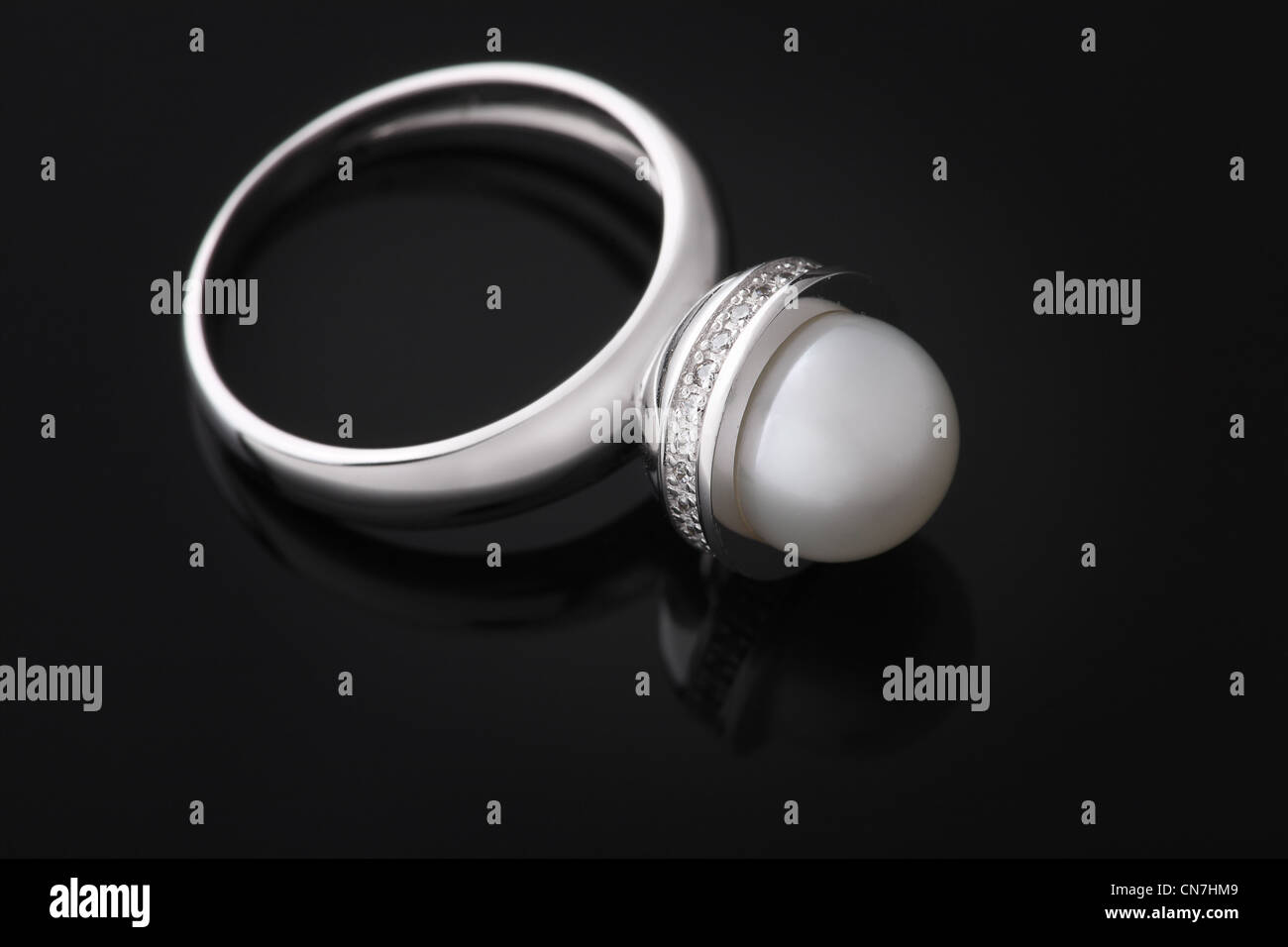 Ring aus Weißgold mit einer Perle auf dem schwarzen Oberfläche spiegeln Stockfoto