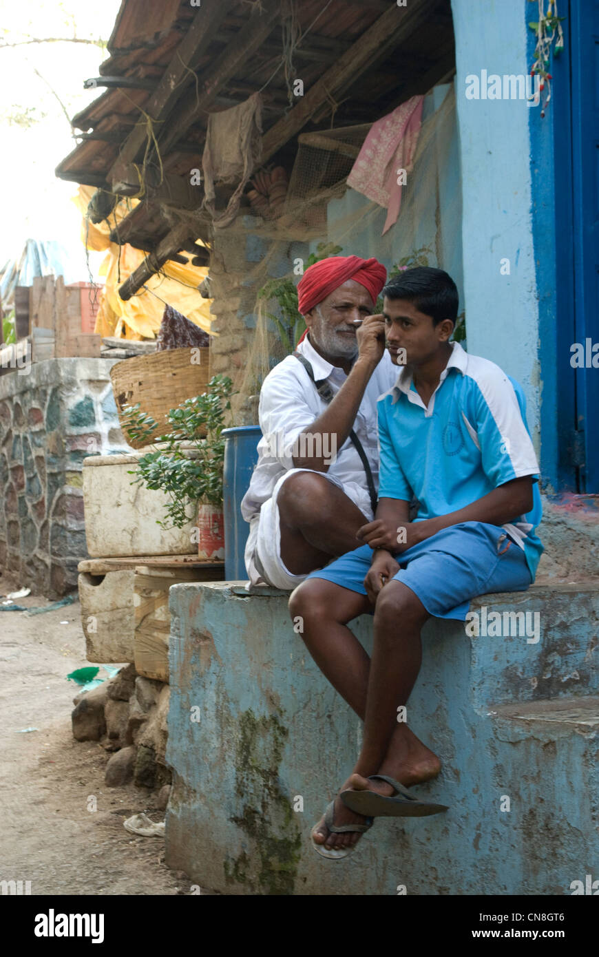 Mann, die Reinigung der Ohren eines Kunden (Teenager) - Szene aus Worli-Kohliwada, Mumbai, Indien Stockfoto