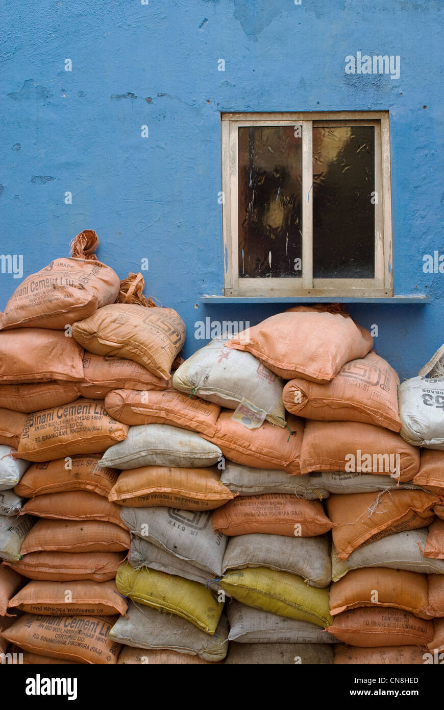 Säcke mit Sand platziert vor einer blauen Wand mit kleinen Fenster - Worli-Kohliwada Stockfoto