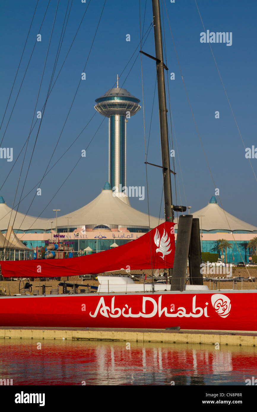 Blick auf Marina Mall und Marina Mall Tower aus Abu Dhabi Marina & Yacht Club. Rote Segelboot namens "Abu Dhabi" im Vordergrund. Stockfoto