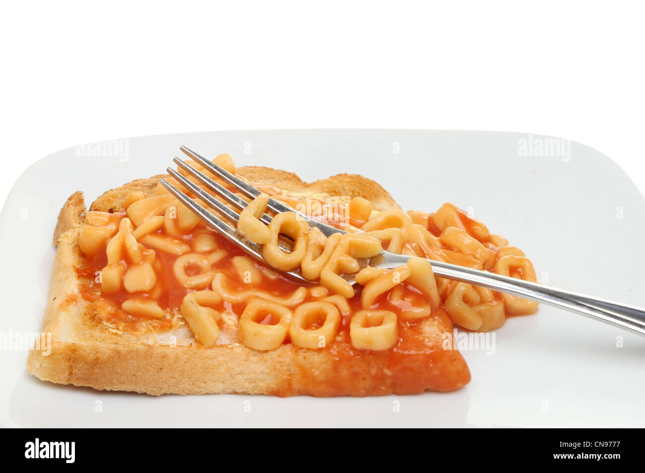 Nahaufnahme einer Kinder-Mahlzeit Alphabet Spaghetti auf Toast auf einem Teller mit einer Gabel Schreibweise liebe Essen Stockfoto