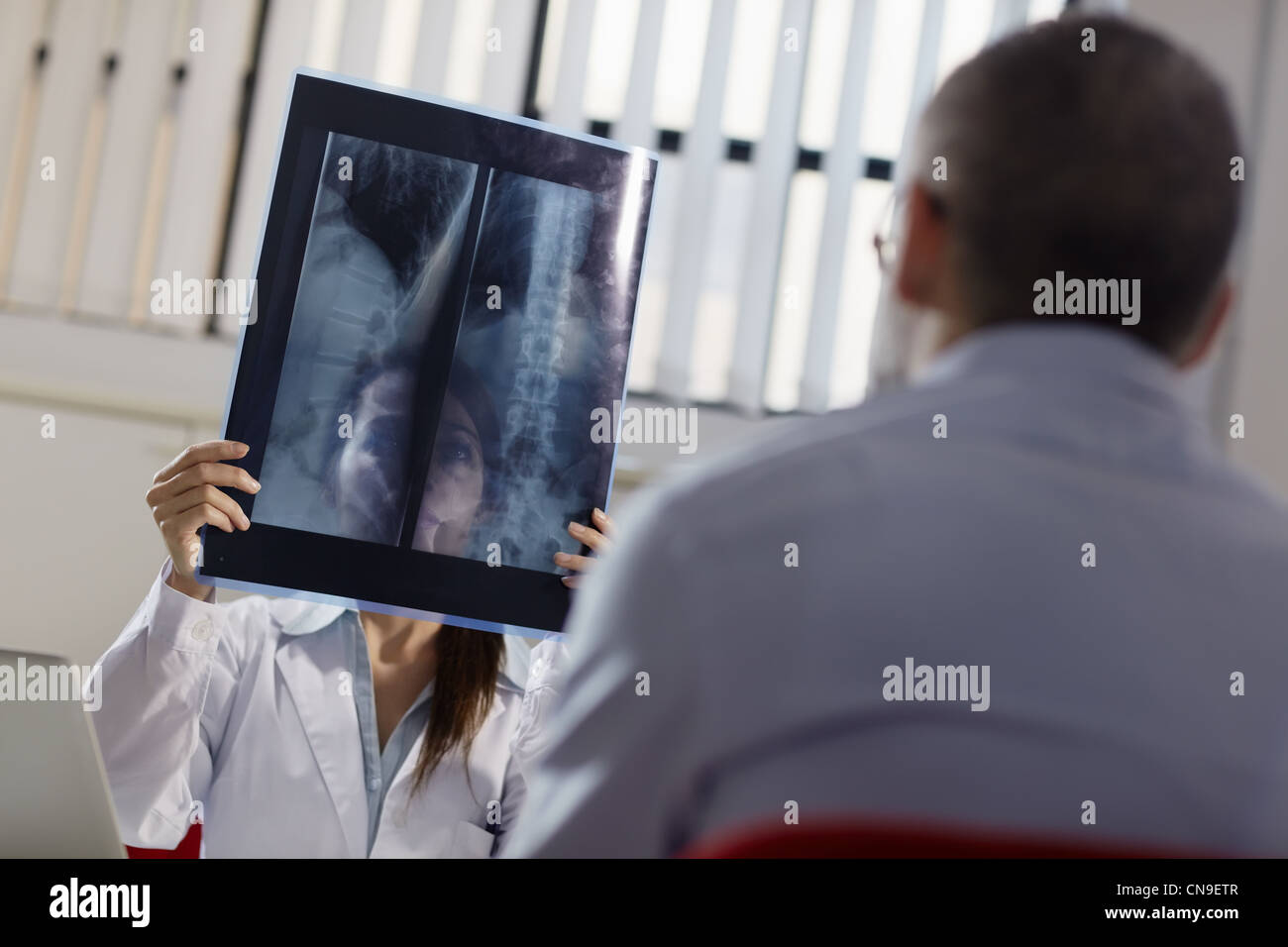 Mitte Erwachsene Frau bei der Arbeit als Arzt in Büro- und Untersuchung Röntgenstrahlen mit Patienten Stockfoto