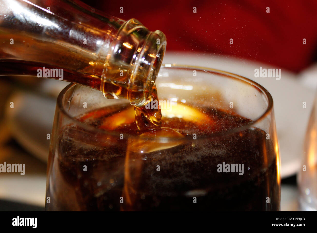 Cola im Glas mit Eis gießen Stockfoto