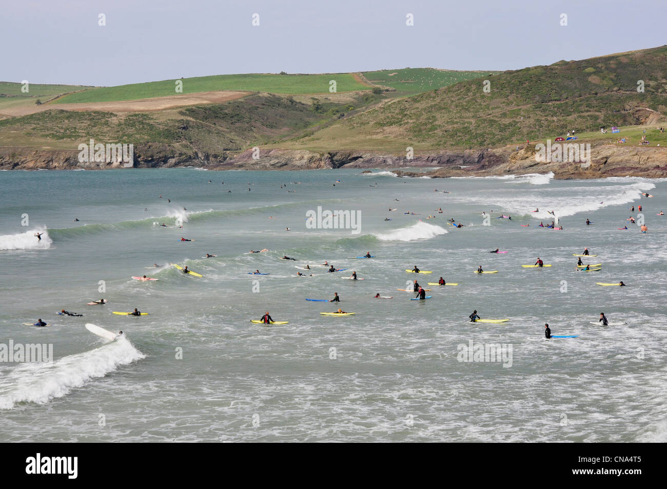 Cornwall - Hayle Bay - Surfer fangen die Brecher - Hintergrund Pentireglaze - Klippen und grüne Felder oben Stockfoto