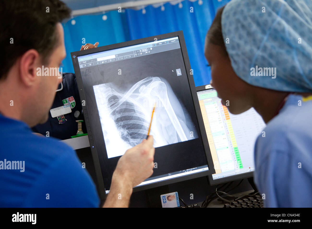 Eine junge schwarze Ärztin spricht mit einem Kollegen über ein Röntgenbild in Unfall- und Notfall UK Stockfoto