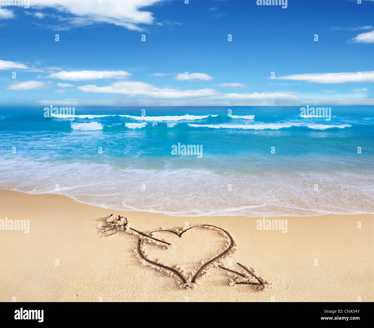 Herz mit Pfeil, als Zeichen der Liebe, direkt am Strand, mit dem Stuhl und Himmel im Hintergrund gezeichnet. Stockfoto