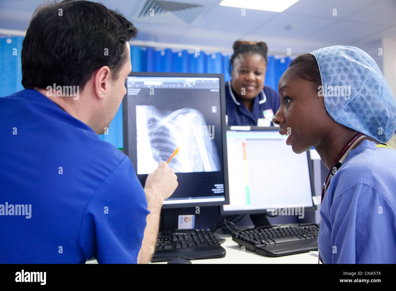 Eine junge schwarze Ärztin spricht mit einem Kollegen über ein Röntgenbild in Unfall- und Notfall UK Stockfoto