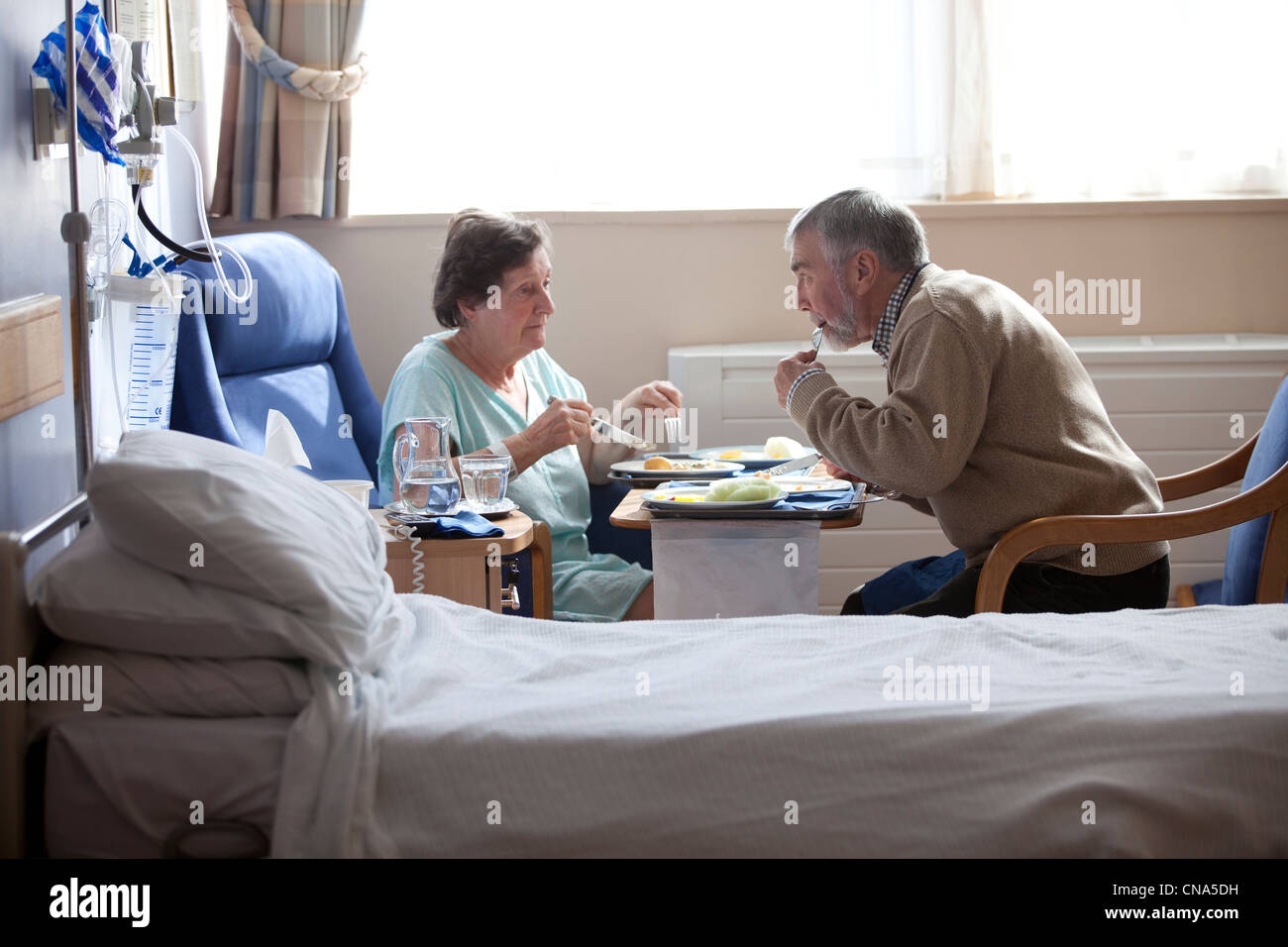 Ein älteres Ehepaar genießen Sie eine Mahlzeit in einem privaten Zimmer im Krankenhaus UK Stockfoto